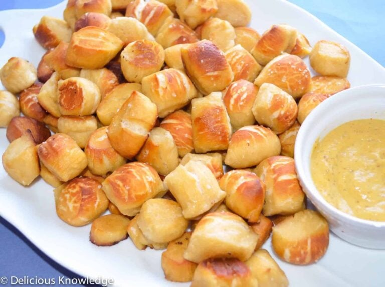Golden Brown Pretzel Bites Served With A Side Of Creamy Cheese Dip On A White Platter Of Homemade Gnocchi.