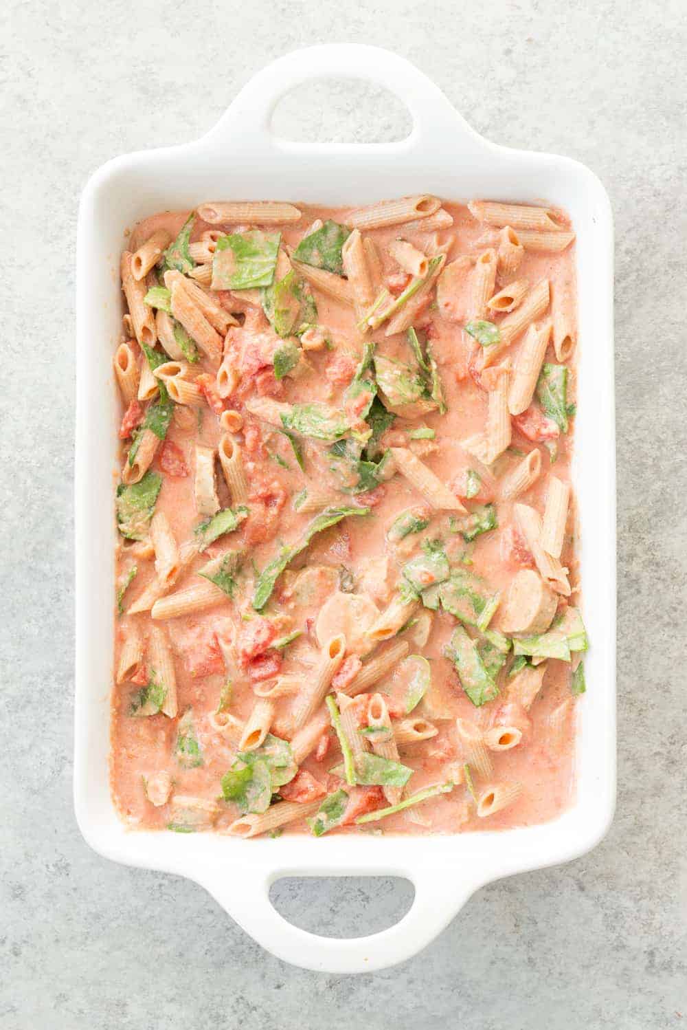 Uncooked pasta in a creamy sauce in a casserole dish