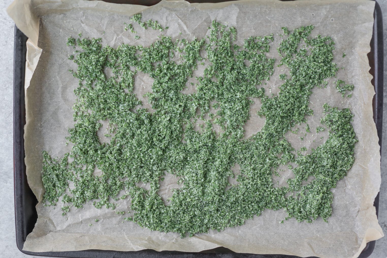 Chopped Green Herbs Spread On Parchment Paper Lining A Baking Tray, Ready For Drying Or Baking.