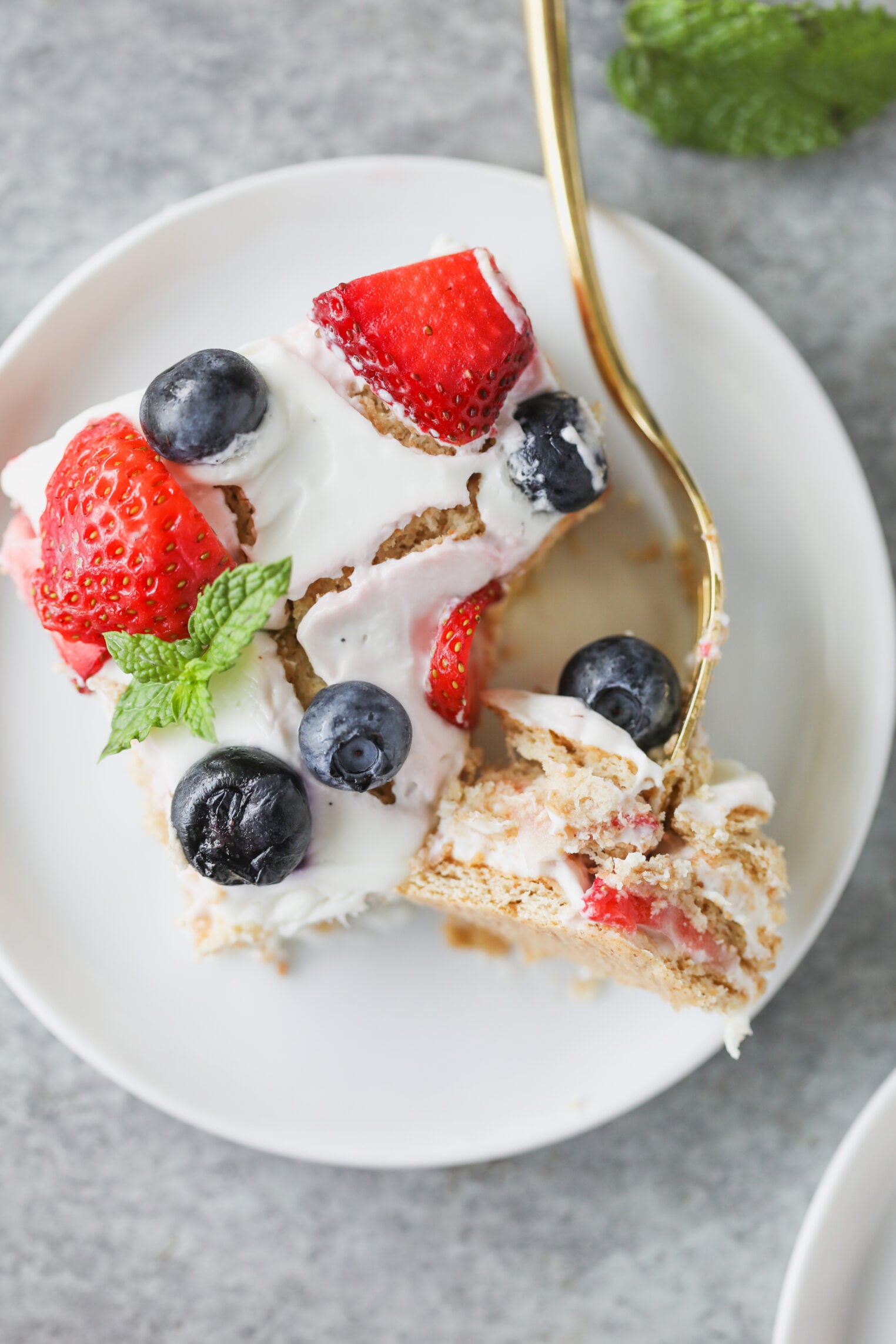 Berry Icebox Cake 9 A Fork Cutting Into A Luscious Berry Icebox Cake Topped With Whipped Cream, Strawberries, Blueberries, And A Mint Leaf, On A White Plate.