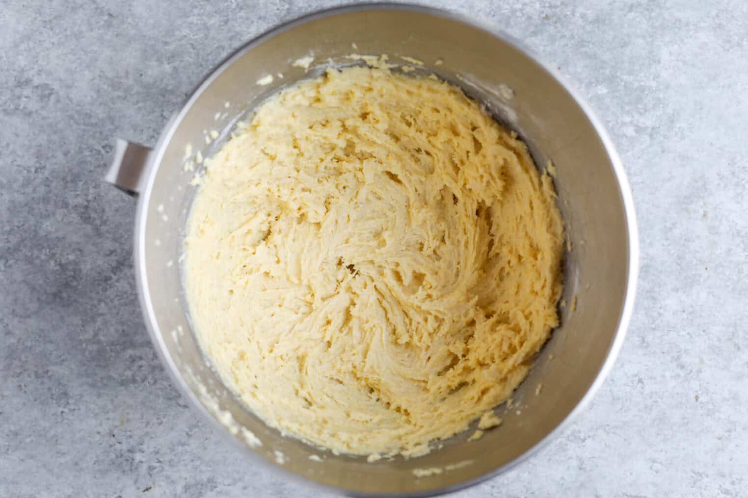 Blackberry Lemon Polenta Cake 6 A Metal Mixing Bowl Filled With Pale, Fluffy Lemon Cookie Dough Sits On A Gray Countertop, Viewed From Above.