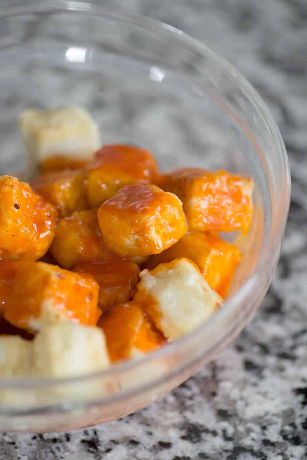 Tofu Cubes Being Coated With Buffalo Sauce