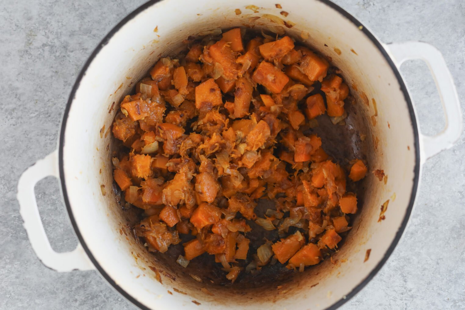 Butternut Squash Risotto 3 Chopped Sweet Potatoes And Onions Sautéed In A White Pot, With Lightly Browned Edges, Evoke The Cozy Flavors Of Butternut Squash Risotto, All Set On A Gray Surface.