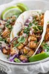 Three Butternut Squash Tacos With Tofu And Limes On A Plate