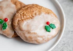 Two vegan sugar cookies with eggnog glaze and holly decoration