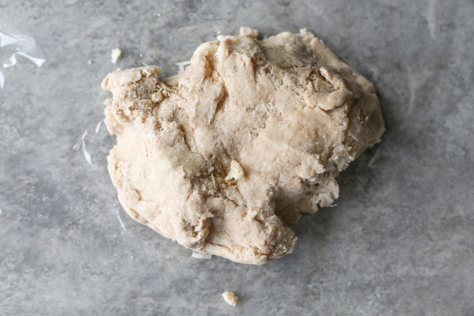 A Rough Ball Of Unbaked Dough Sits On A Gray, Lightly Floured Surface, Ready To Be Kneaded Or Rolled Out For A Rustic Blueberry Galette.