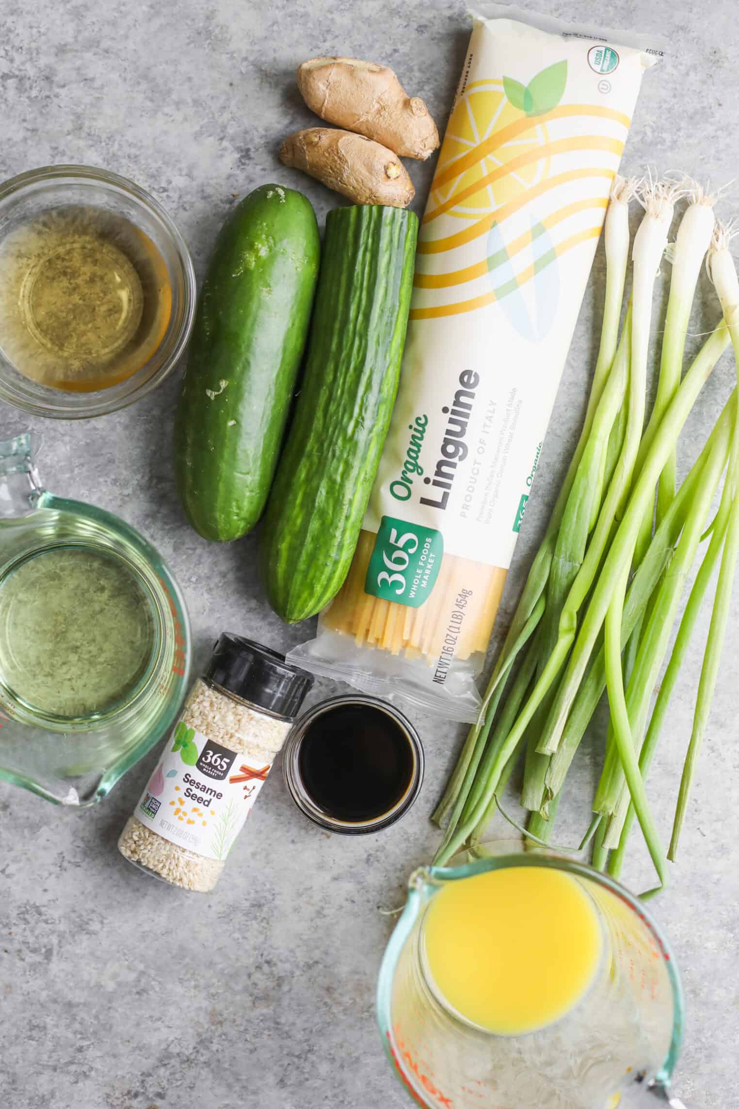 Cold Sesame Noodles With Cucumbers 3 A Flat Lay Of Ingredients On A Gray Surface: A Bunch Of Scallions, Cucumber, Fresh Ginger, Organic Linguine For Cold Sesame Noodles, Sesame Seeds, Soy Sauce, Rice Vinegar, And Orange Juice In Glass Measuring Cups.