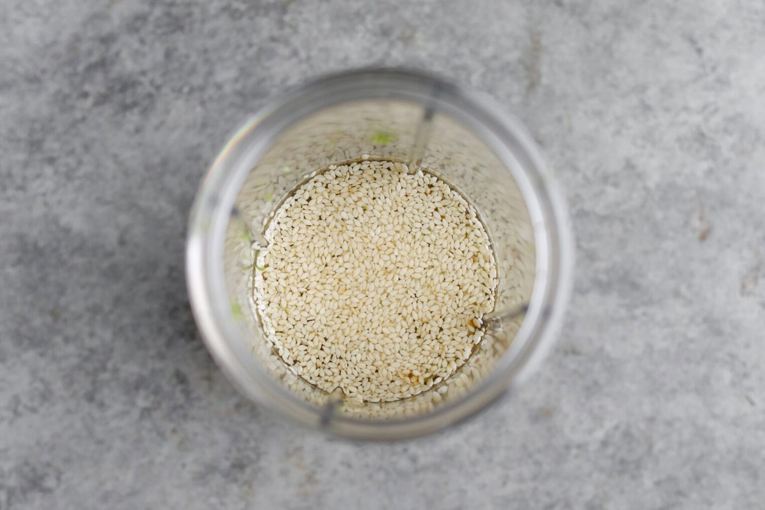 Cold Sesame Noodles With Cucumbers 4 Overhead View Of A Blender Cup Filled With Uncooked White Sesame Seeds, Ready To Be Blended For Cold Sesame Noodles, Sitting On A Gray Countertop.