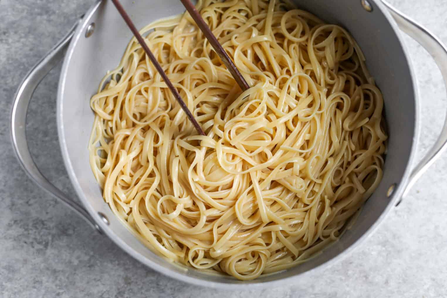 Cold Sesame Noodles With Cucumbers 6 A Pot Of Cooked Linguine Pasta, Reminiscent Of Cold Sesame Noodles, Being Stirred With A Pair Of Wooden Chopsticks, Placed On A Light Gray Surface.