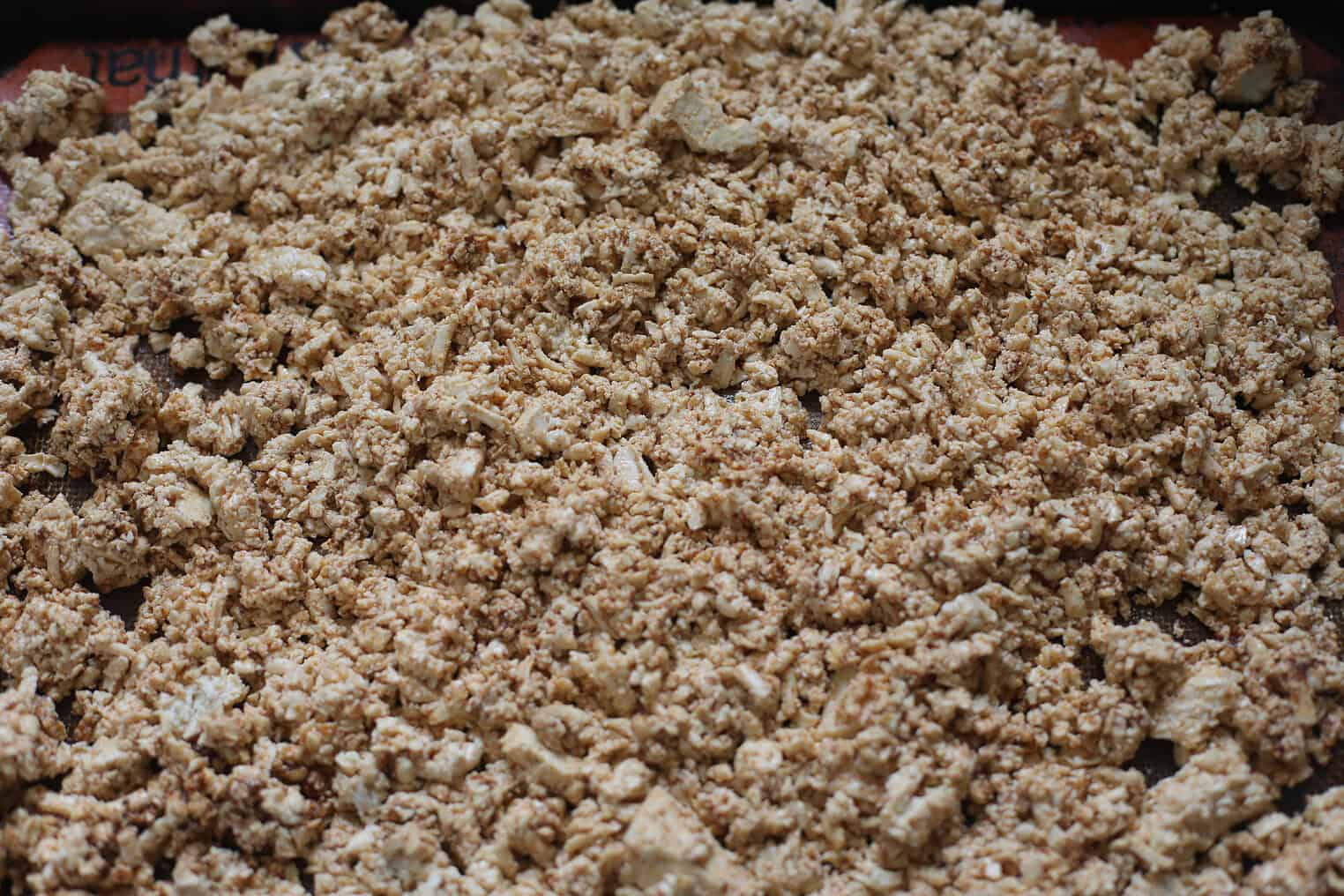 Crispy Tofu Tacos with Cashew Lime Crema 6 Crumbled Tofu Spread Out On A Baking Sheet, Coated In A Light Brown Seasoning, Ready To Be Baked For Crispy Tofu Tacos. The Uneven Pieces Create A Rough, Crumbly Surface Perfect For Taco Fillings.