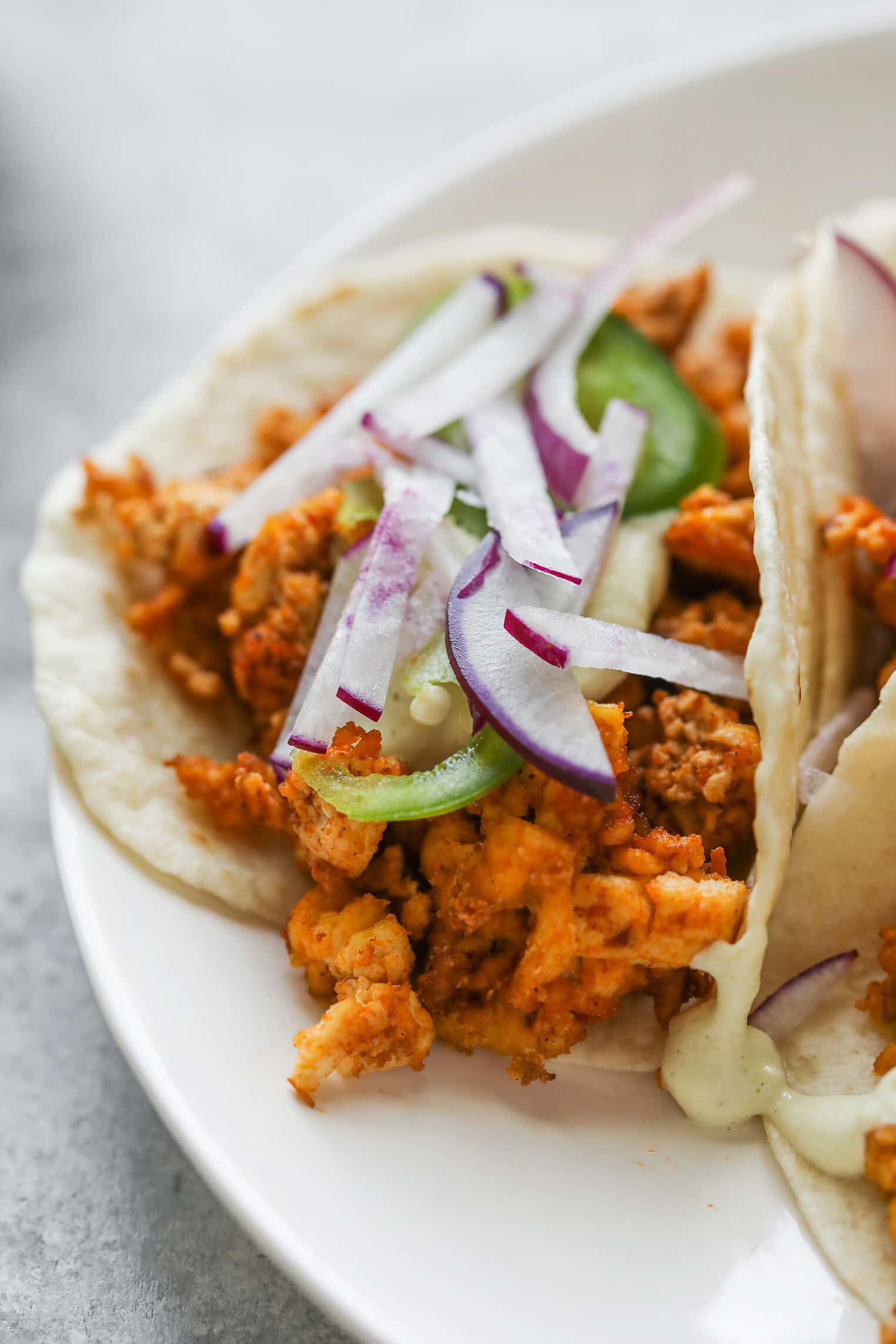 Crispy Tofu Tacos with Cashew Lime Crema 3 A Close-Up Of A Soft Taco Filled With Seasoned Ground Meat, Topped With Sliced Radishes, Red Onions, And JalapeƱo Slices On A White PlateāPerfect For Fans Of Crispy Tofu Tacos Looking To Try Something New.
