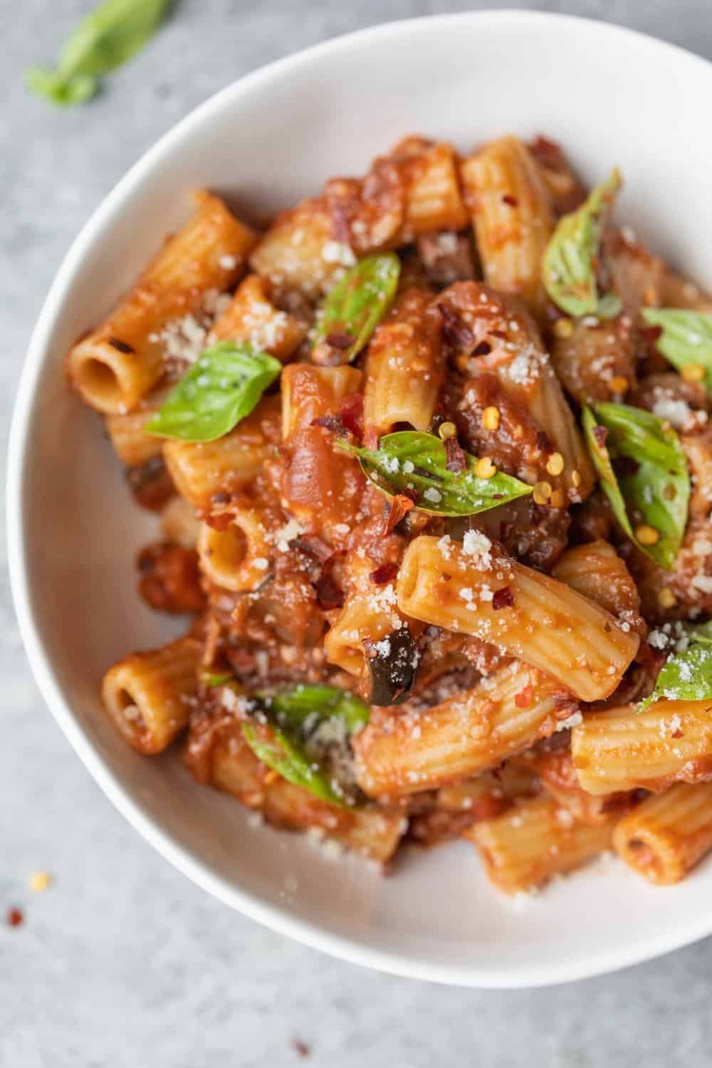 Pasta With Eggplant Bolognese Sauce With Fresh Basil Leaves And Red Pepper Flakes