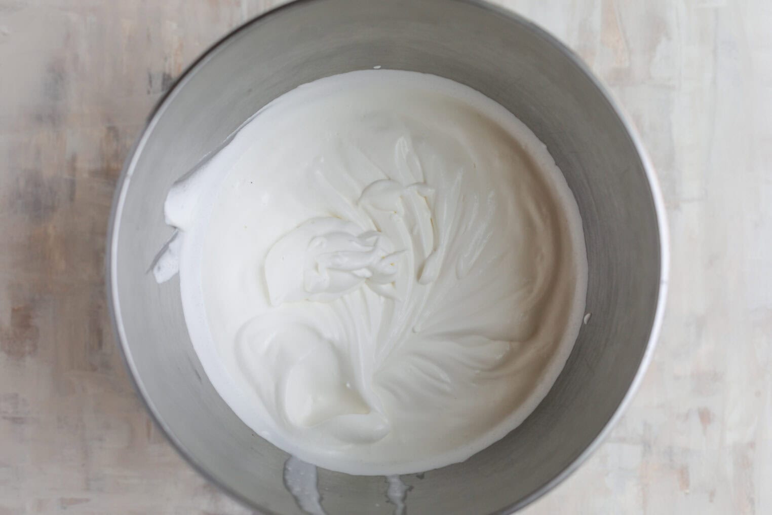 Fresh Berry Trifle 5 A Metal Mixing Bowl Containing Stiffly Whipped Egg Whites, With Visible Peaks And A Smooth, Glossy Texture—Perfect For Folding Into A Luscious Berry Trifle. The Bowl Is Placed On A Light-Colored Surface.