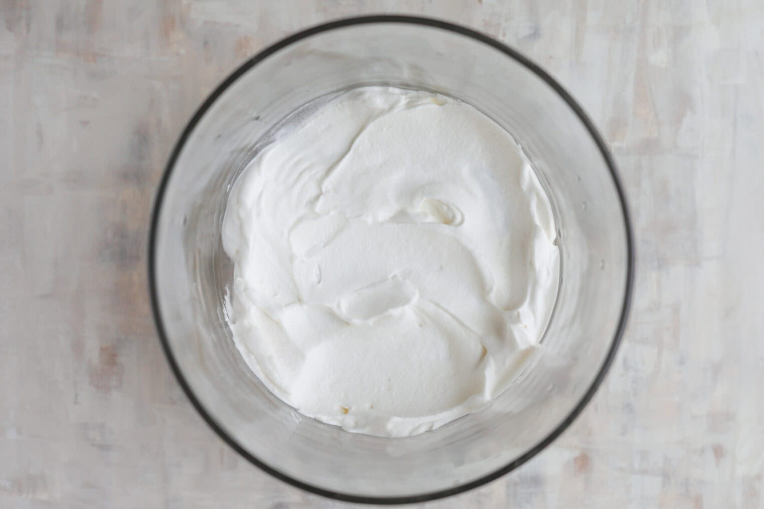 Fresh Berry Trifle 7 A Glass Bowl Filled With Smooth, Whipped White Cream For A Berry Trifle Sits On A Light-Colored, Textured Surface, Viewed From Above.