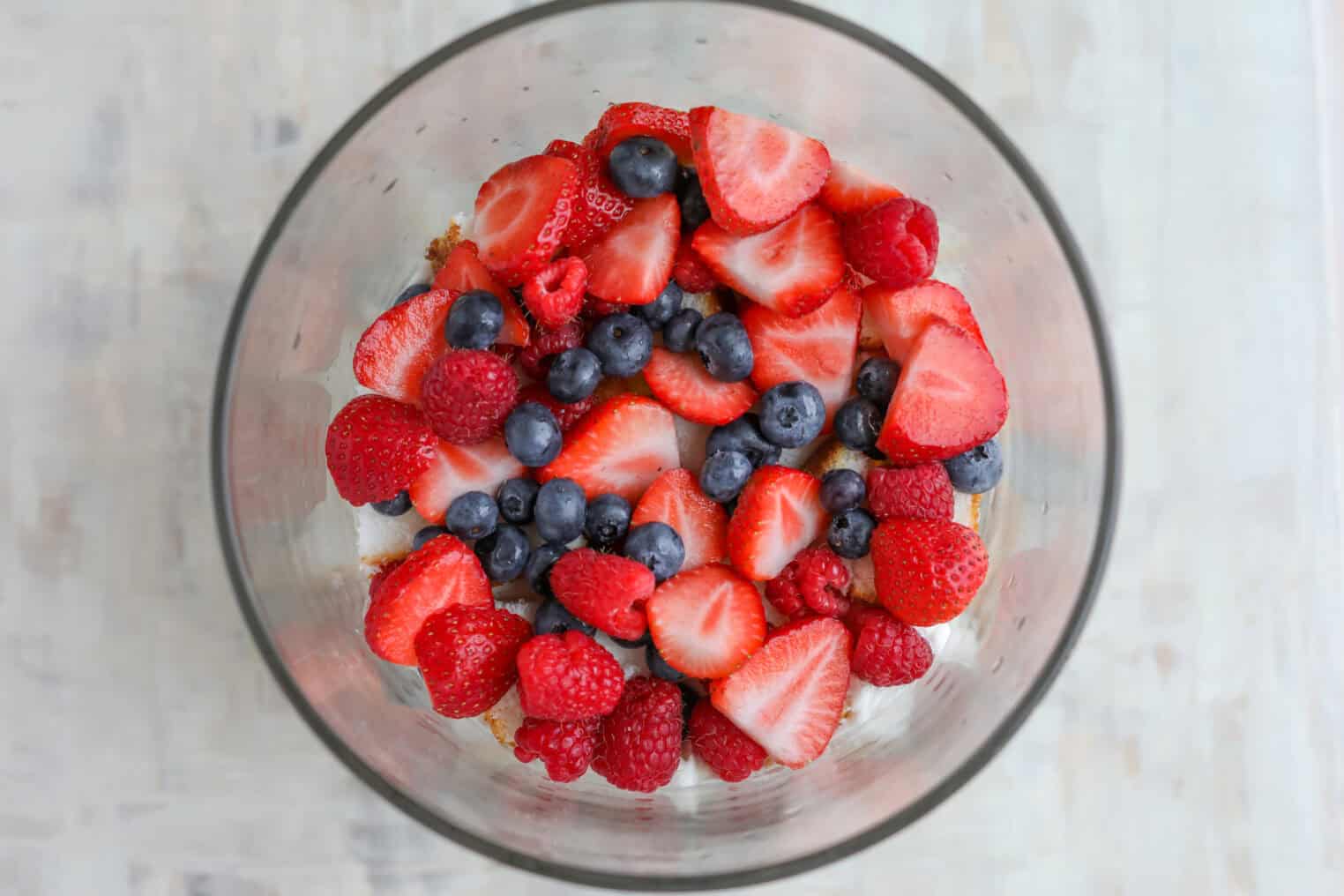 Fresh Berry Trifle 9 A Glass Bowl Filled With Fresh Strawberries, Blueberries, And Raspberries Arranged On Top Of A Creamy White Layer Creates A Vibrant Berry Trifle, Seen From Above.