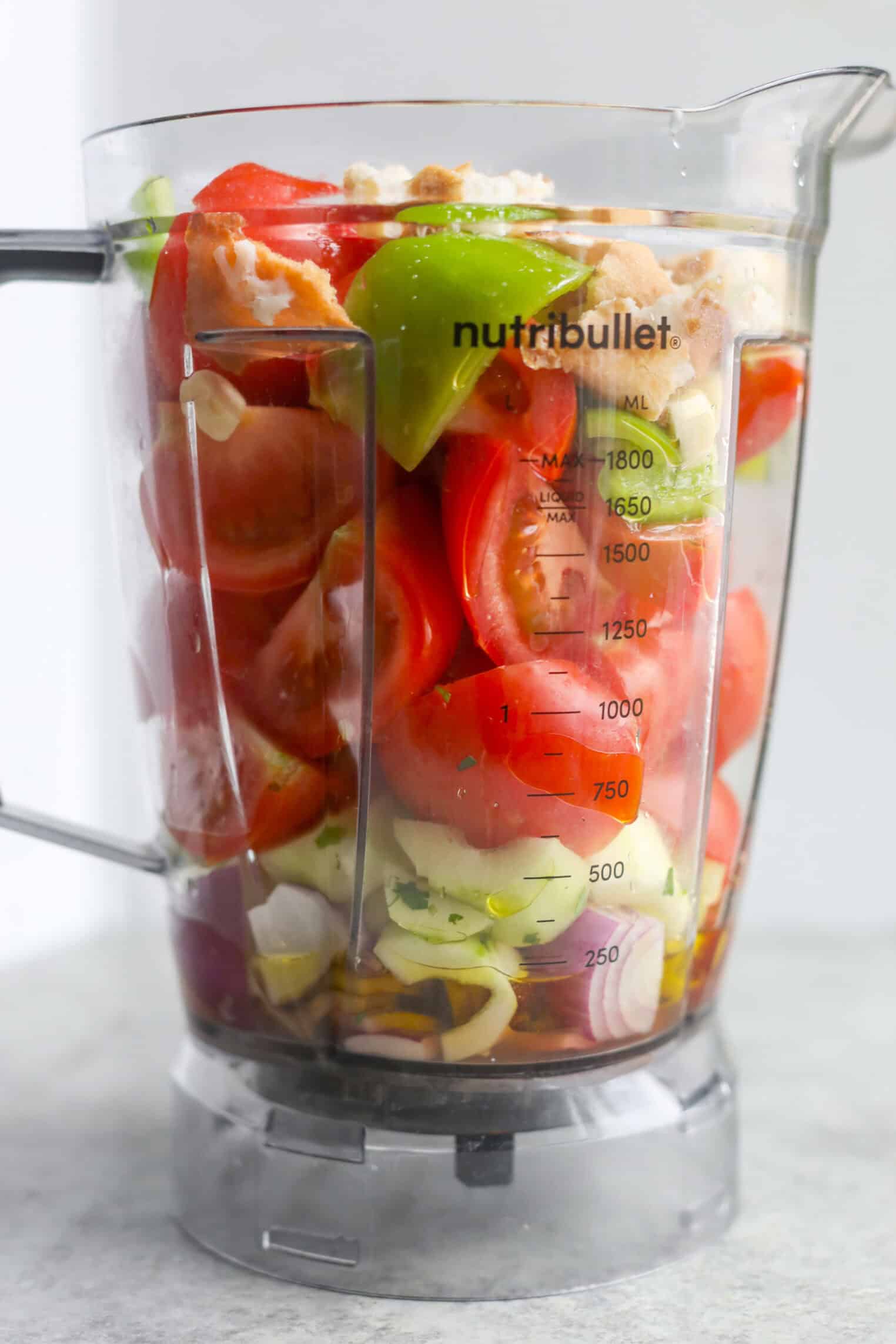 Gazpacho 2 A Nutribullet Blender Cup Filled With Chopped Vegetables, Including Tomatoes, Green Bell Peppers, Onions, And What Appears To Be Bread Pieces—Classic Gazpacho Ingredients—Ready For Blending. Measurement Markings Are Visible On The Blender Cup.
