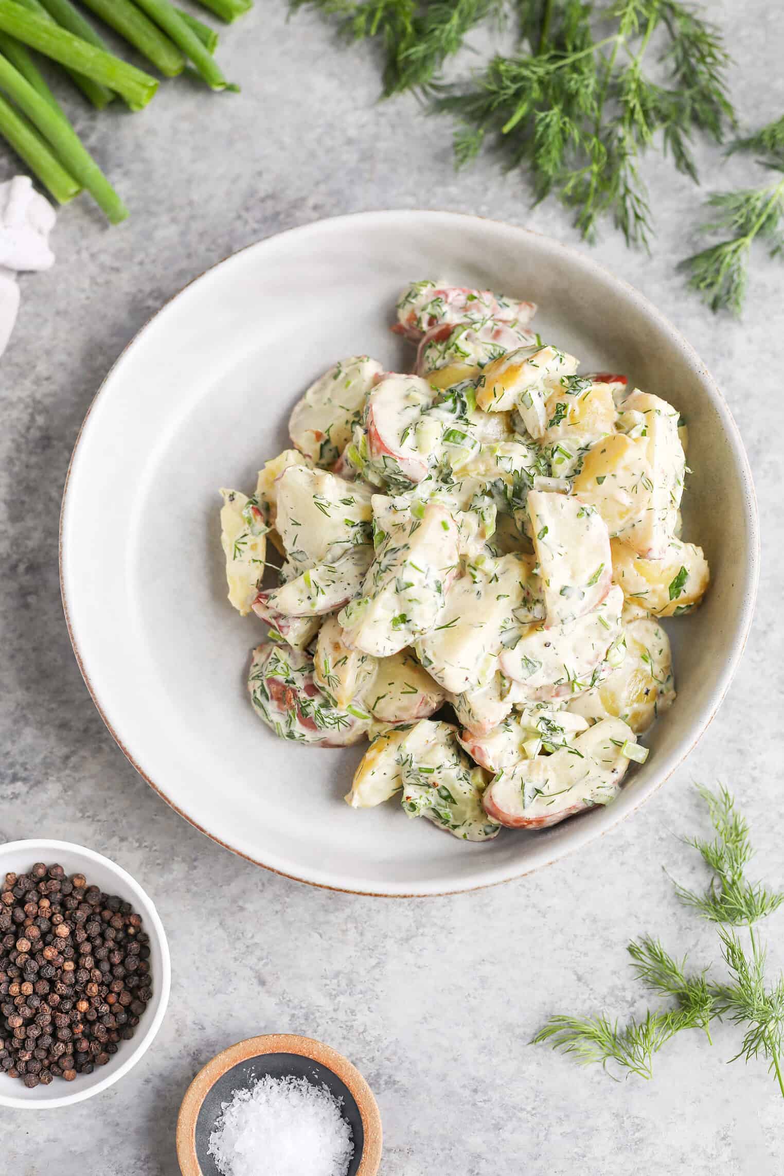 Creamy Herbed Potato Salad 1 A Bowl Of Herbed Potato Salad Garnished With Chopped Dill, Surrounded By Fresh Dill, Green Onions, Black Peppercorns, And A Small Dish Of Salt On A Light Gray Surface.
