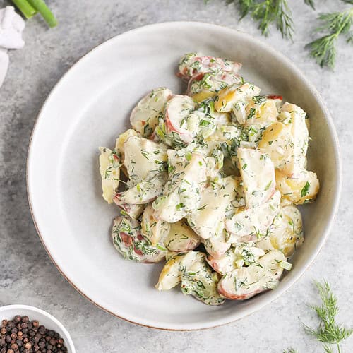 Creamy Herbed Potato Salad 13 A Bowl Of Herbed Potato Salad Garnished With Chopped Dill, Surrounded By Fresh Dill, Green Onions, Black Peppercorns, And A Small Dish Of Salt On A Light Gray Surface.