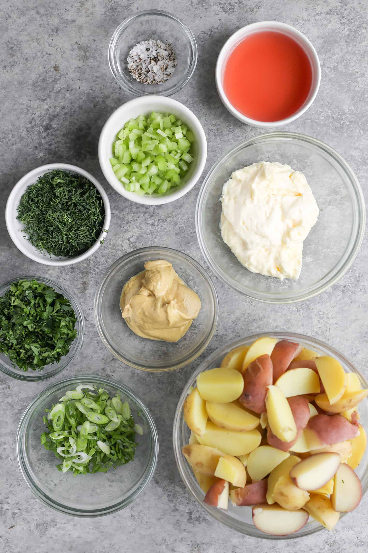 Creamy Herbed Potato Salad 3 Various Ingredients For A Herbed Potato Salad Are Arranged In Glass Bowls On A Gray Surface, Including Chopped Potatoes, Mayonnaise, Mustard, Celery, Sliced Green Onions, Chopped Herbs, Vinegar, And Salt.