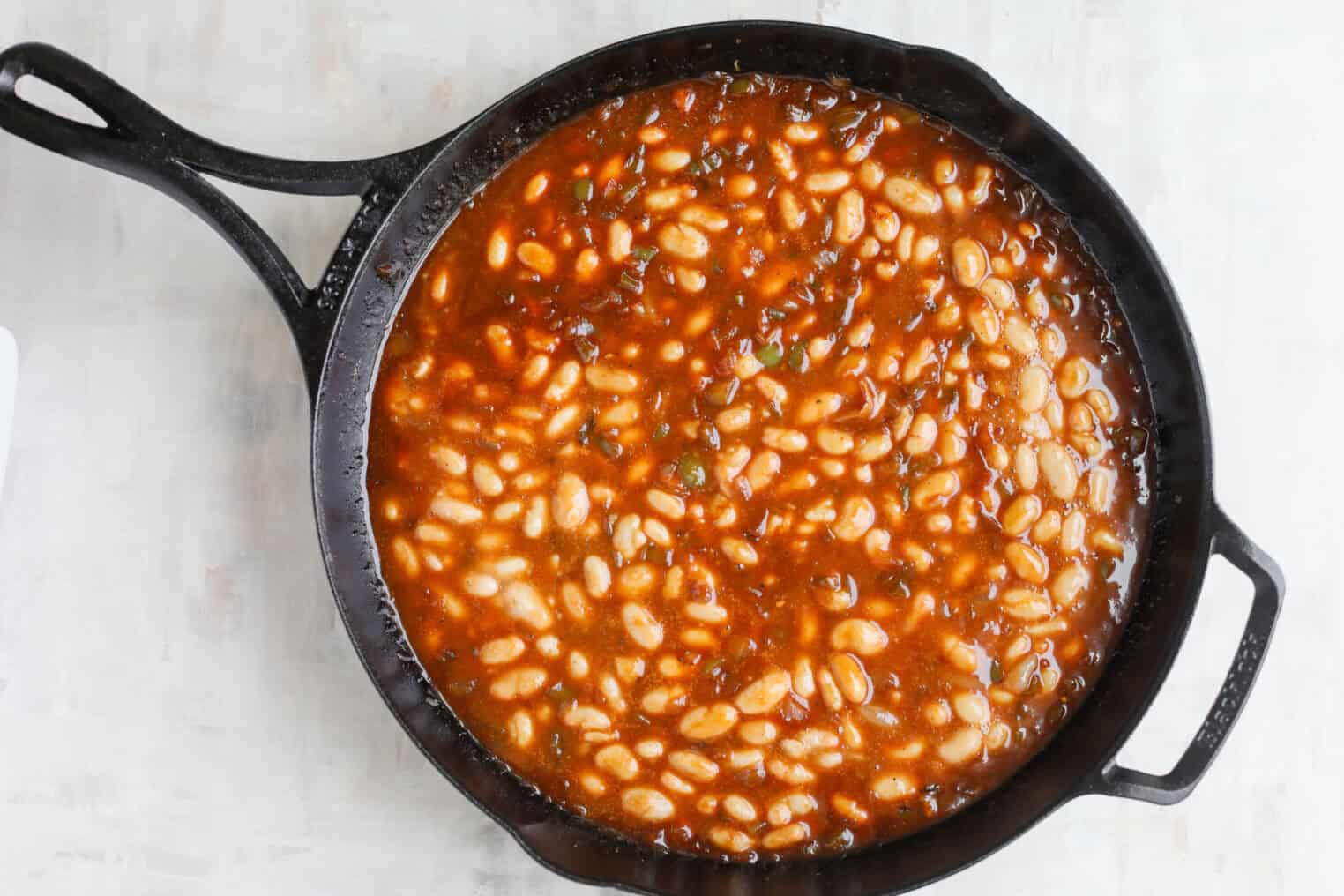 Smoky Vegetarian Baked Beans 6 A Cast-Iron Skillet Filled With Vegetarian Baked Beans In A Rich, Reddish-Brown Sauce, Resting On A Light-Colored Surface.