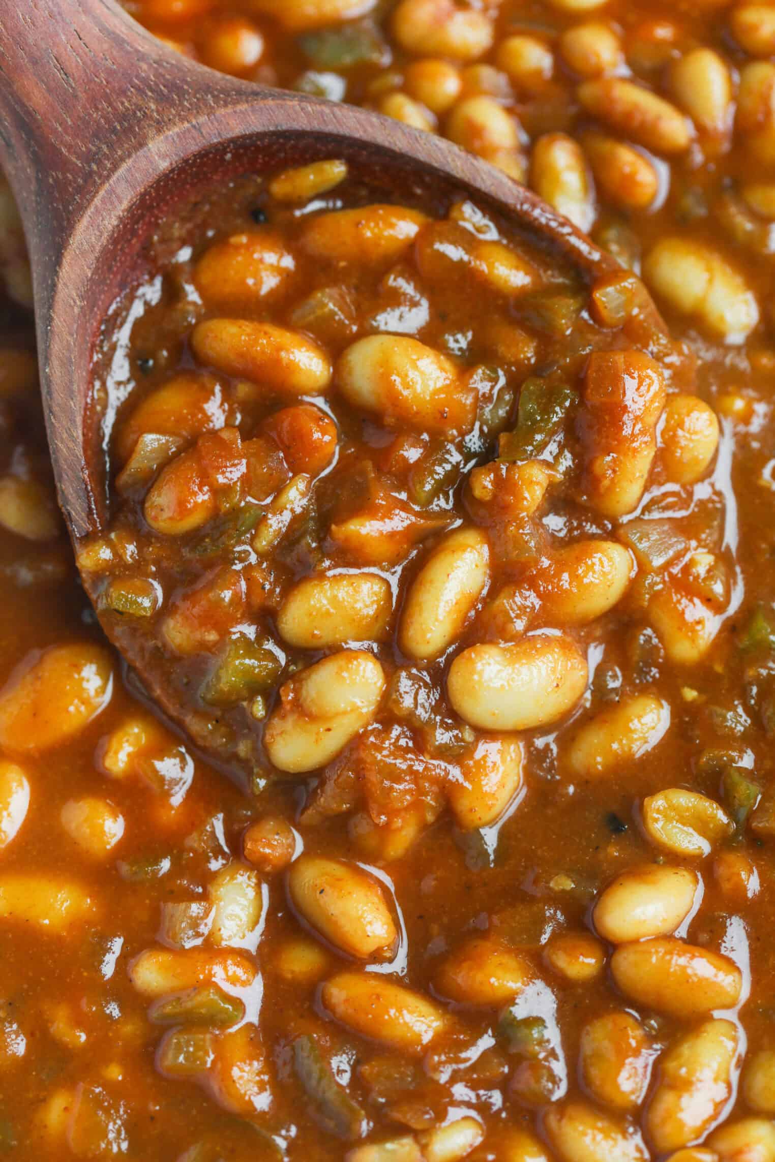 Smoky Vegetarian Baked Beans 7 A Close-Up Of Vegetarian Baked Beans In A Rich, Reddish-Brown Sauce, With A Wooden Spoon Scooping Some Of The Beans. The Thick Sauce Appears Perfectly Seasoned With Herbs And Spices.