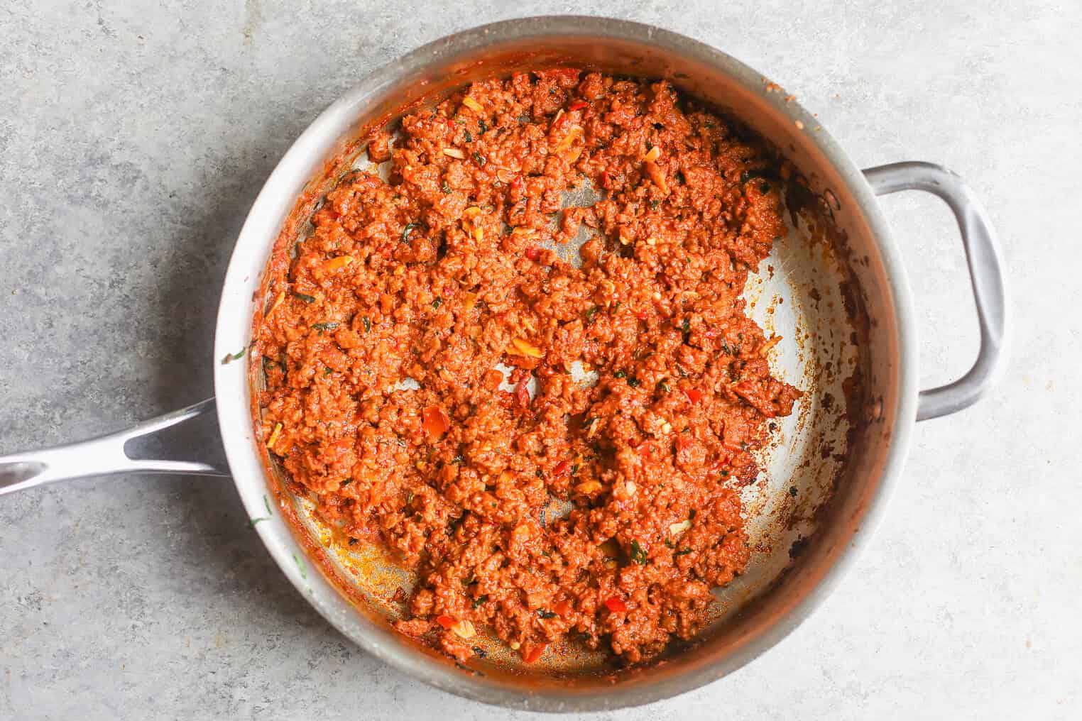 A Metal Pan On A Gray Surface Filled With Cooked Ground Beef Mixed With Tomato Sauce And Diced Vegetables, Resembling A Seasoned Impossible Bolognese Or Plant-Based Pasta Sauce.