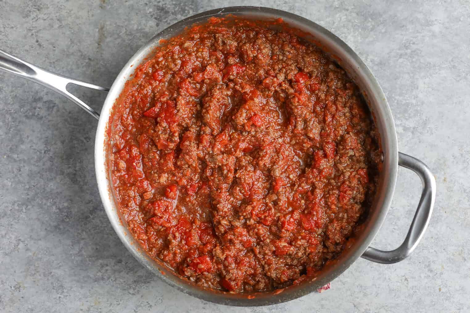 Impossible Lasagna 8 A Stainless Steel Pan Filled With Chunky Red Meat Sauce, Likely A Tomato-Based Bolognese For Impossible Lasagna, Sits On A Gray Countertop.