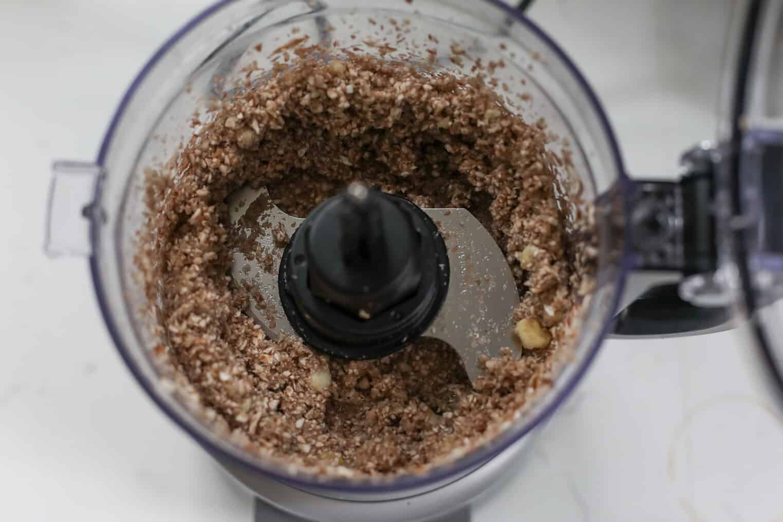 Impossible Lasagna 6 A Food Processor With A Mixture Of Blended Oats And Nuts For An Impossible Lasagna Filling, Viewed From Above. The Ingredients Appear Partially Ground And Moist, Sitting Around The Central Blade.