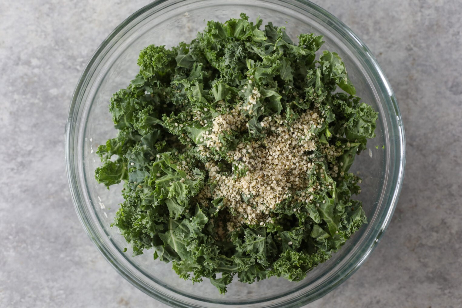 Quinoa Kale Salad 5 A Glass Bowl Filled With Fresh Quinoa Kale Salad, Topped With A Sprinkle Of White Sesame Seeds, Set On A Light Gray Surface.