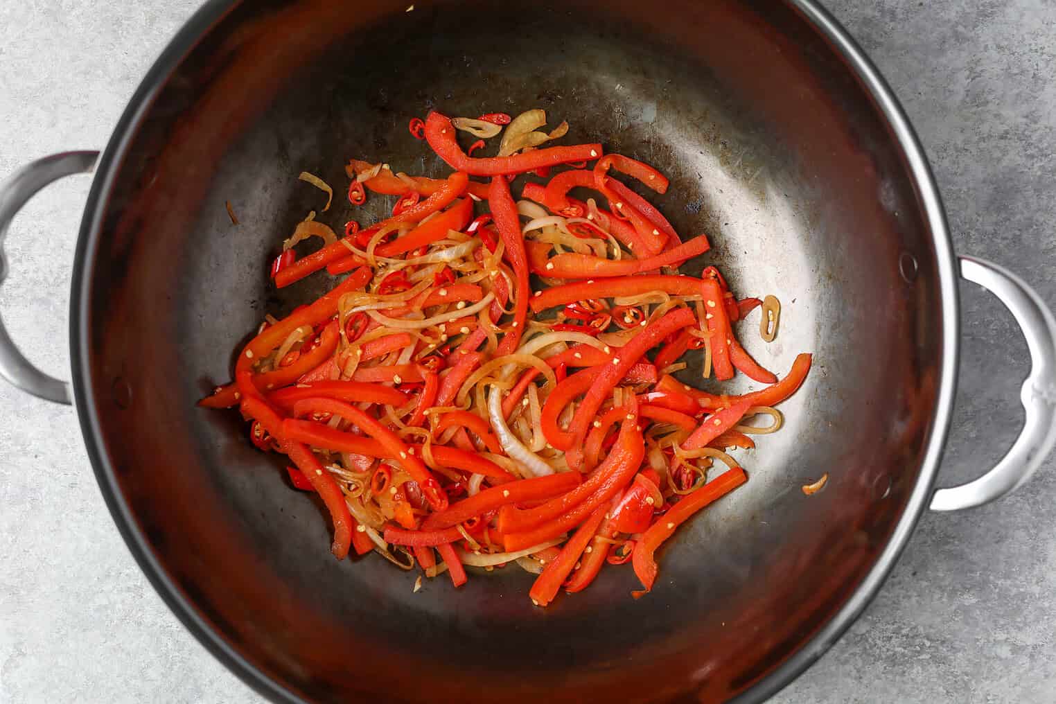 Kung Pao Tofu 8 Sautéed Red Bell Pepper Strips And Sliced Onions In A Large Metal Pan On A Gray Surface, Perfect For Adding To Kung Pao Tofu Dishes.