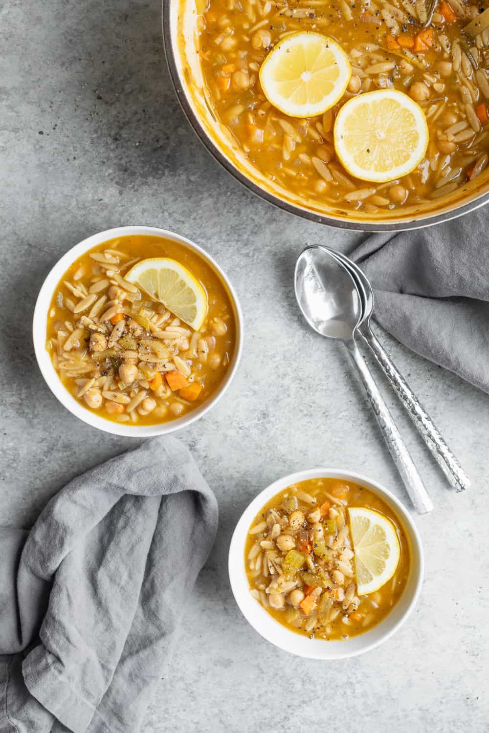 Two Bowls Of Lemon Chickpea Orzo Soup With Larger Soup Pan