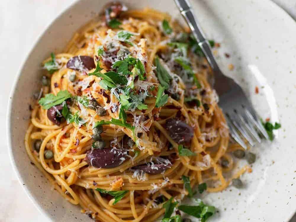 bowl of puttanesca pasta with olives and capers