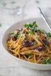 bowl of one pot pasta puttanesca with olives, capers and parsley