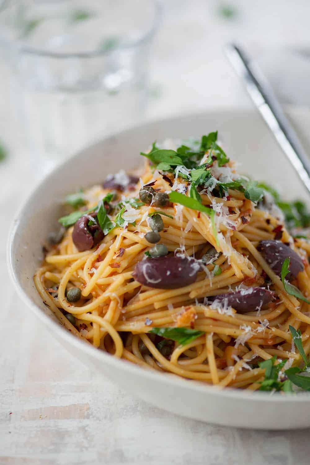 Bowl Of One Pot Pasta Puttanesca With Olives, Capers And Parsley