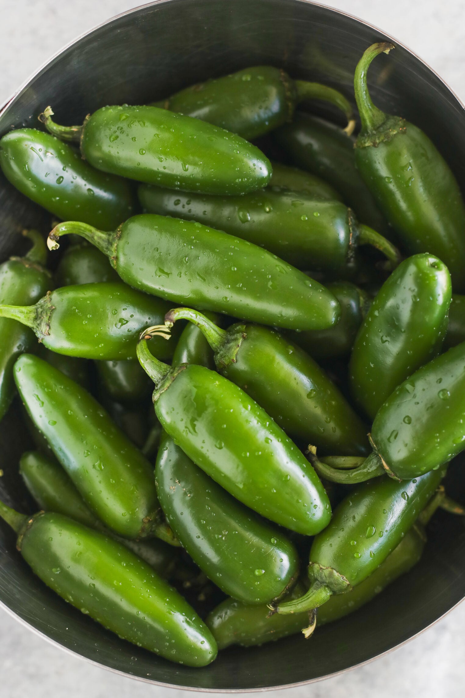 Pickled Jalapeños (Canning Recipe) 4 A Metal Bowl Filled With Fresh, Green Jalapeño Peppers, With Water Droplets Visible On Their Surfaces, Perfect For Making Tangy Pickled Jalapenos.