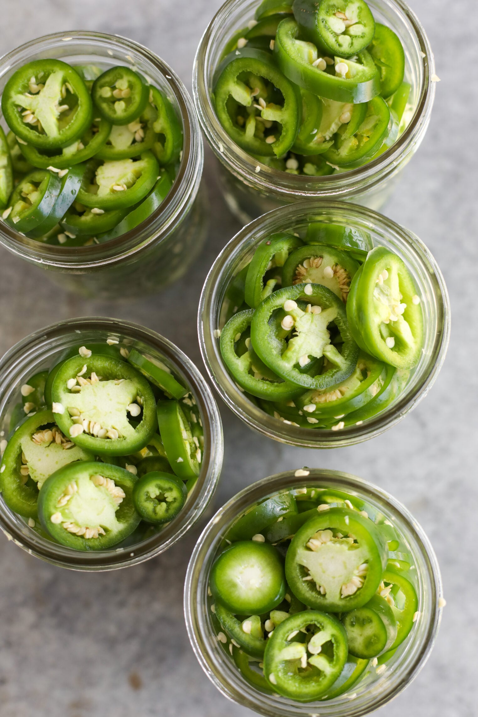 Pickled Jalapeños (Canning Recipe) 7 Five Glass Jars Filled With Sliced Pickled Jalapenos, Viewed From Above, On A Gray Surface.