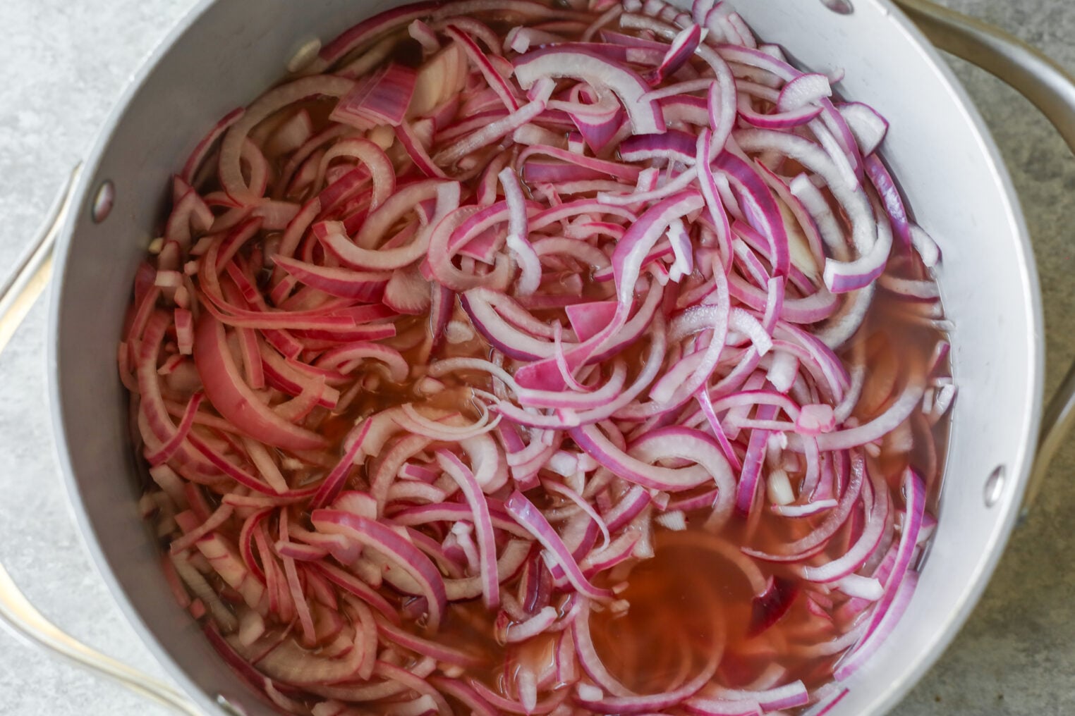 Pickled Red Onions 6 Thinly Sliced Pickled Red Onions Soaking In A Light-Colored Pickling Liquid Inside A Metal Pot.