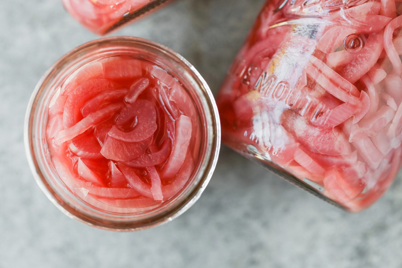 Pickled Red Onions 10 A Top-Down View Of Two Glass Jars Filled With Pickled Red Onions.