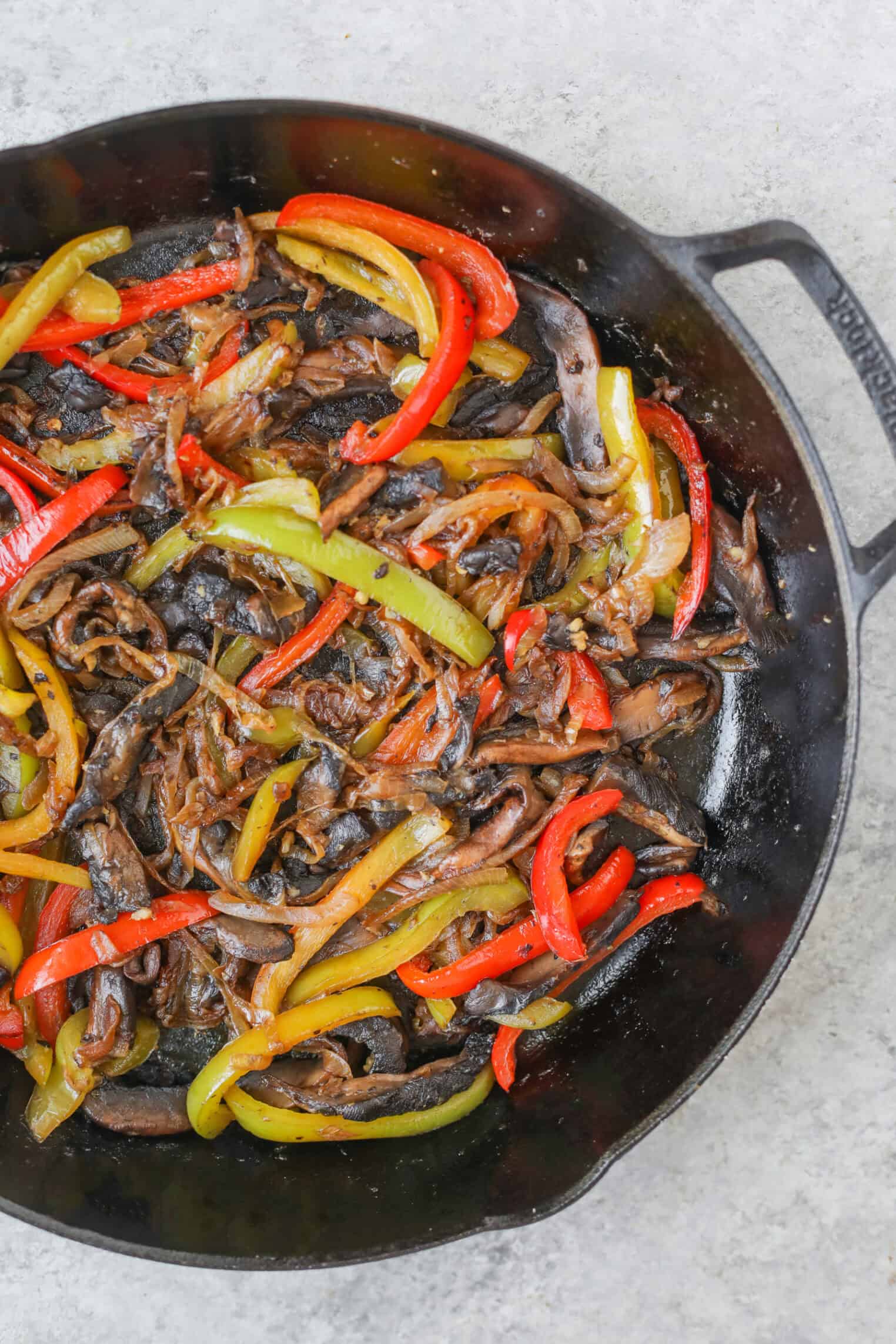 Portobello Cheesesteak Sandwiches 5 A Cast Iron Skillet Filled With Sautéed Red And Green Bell Peppers And Sliced Mushrooms—Perfect For Making Portobello Cheesesteak Sandwiches—Rests On A Light Gray Surface.