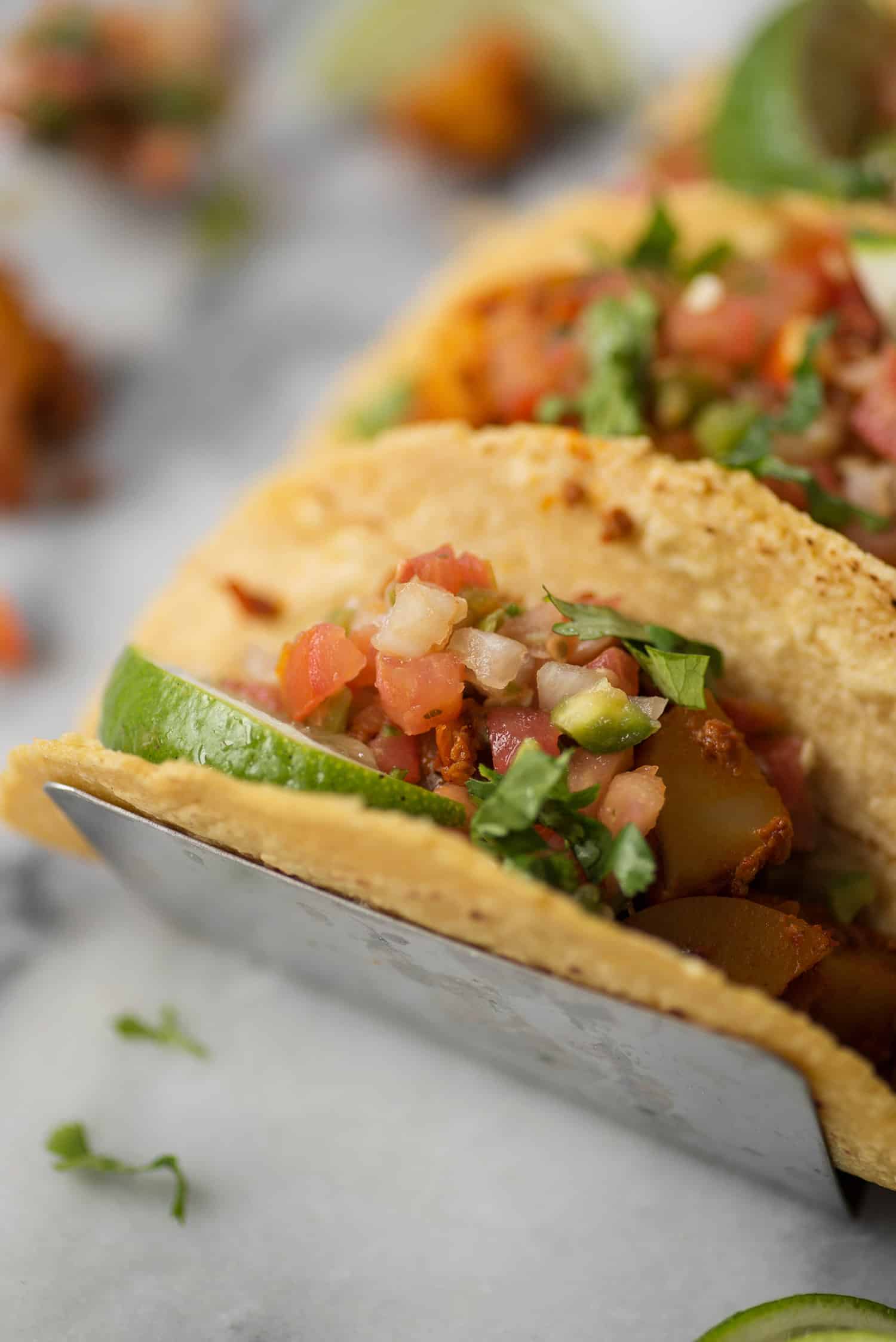 close up of vegan chorizo and potato taco with pico de gallo and lime 