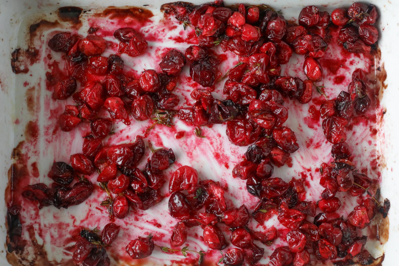 Roasted Cranberries Spread Across A White Baking Dish, With Streaks Of Red Juices And Some Browned Spots Along The Edges—Perfect For Topping A Wild Rice And Kale Salad.
