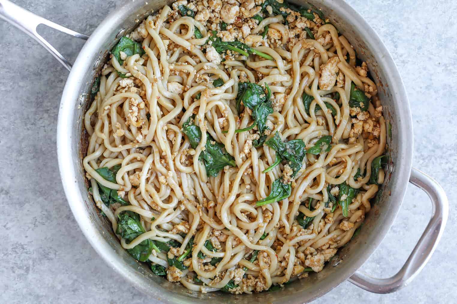 Sesame Garlic Stir Fry Noodles 9 A Large Metal Pan Filled With Stir Fry Noodles, Ground Meat, Wilted Spinach, And A Savory Sauce, Viewed From Above On A Gray Countertop.