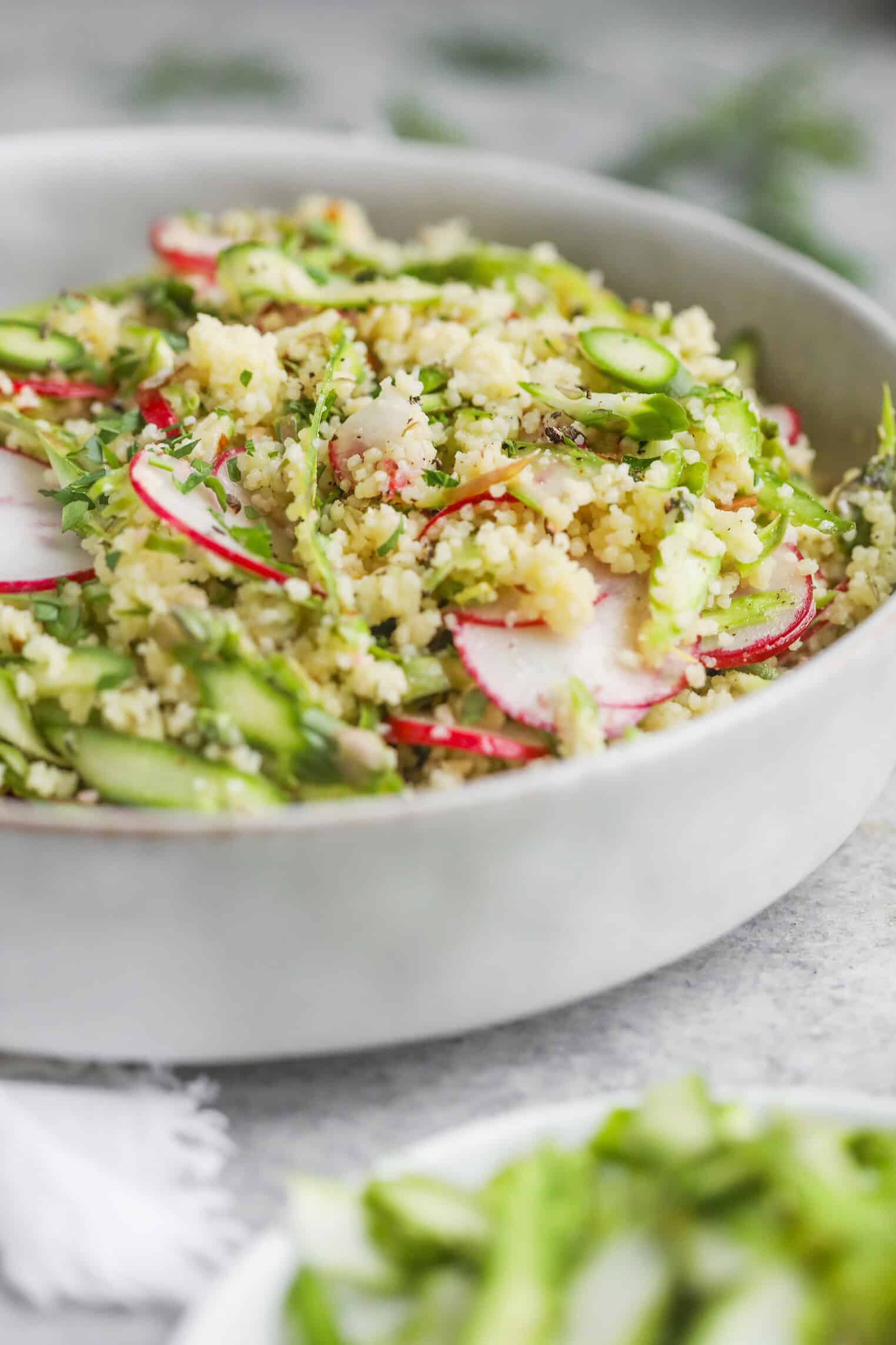 Shaved Asparagus Spring Salad 8 A Close-Up Of A Bowl Filled With Shaved Asparagus Spring Salad, Featuring Couscous, Sliced Radishes, And Fresh Herbs, Beautifully Arranged On A Light, Neutral Background.