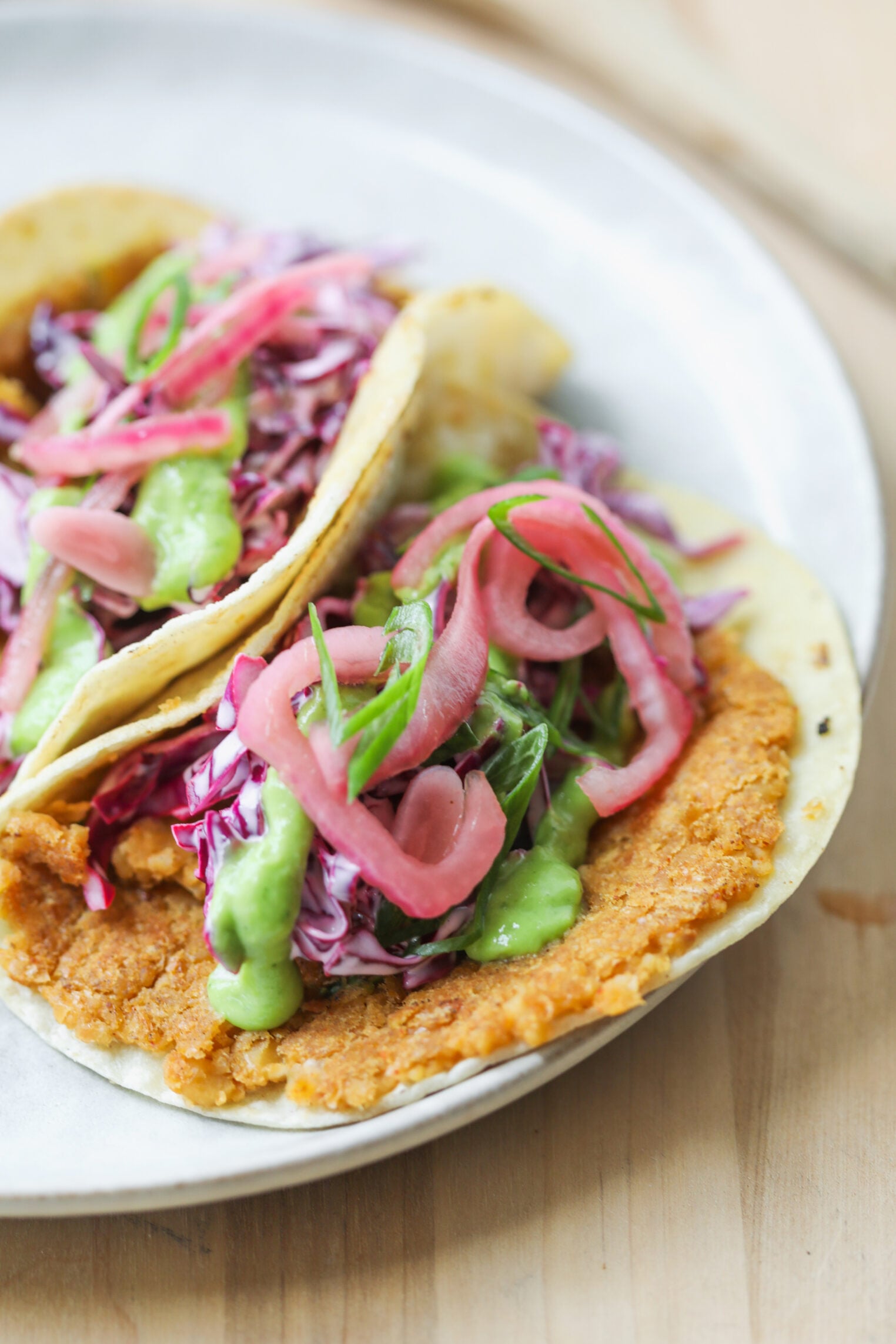 Smashed Chickpea Tacos 2 Two Soft Corn Tortillas Filled With Smashed Chickpea Tacos, Refried Beans, Shredded Purple Cabbage, Pickled Onions, Green Sauce, And Sliced Scallions, Served On A White Plate.
