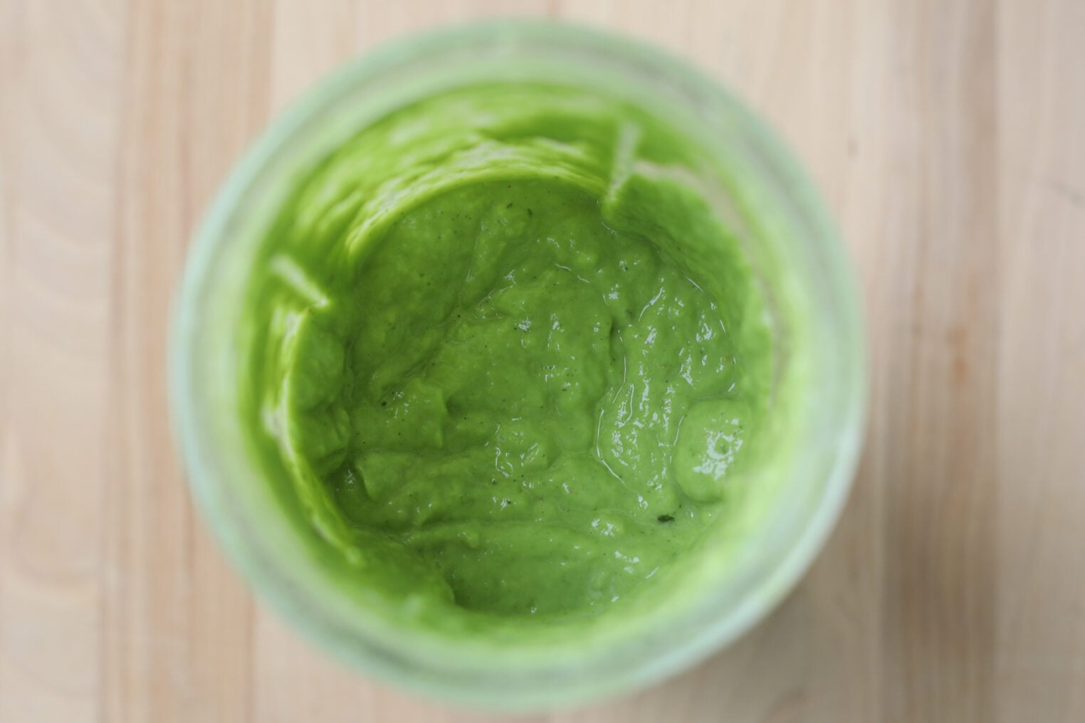 Smashed Chickpea Tacos 6 A Top-Down View Of A Glass Jar Filled With Thick, Creamy Green Sauce Or Puree—Perfect For Drizzling Over Smashed Chickpea Tacos—Placed On A Light Wooden Surface.