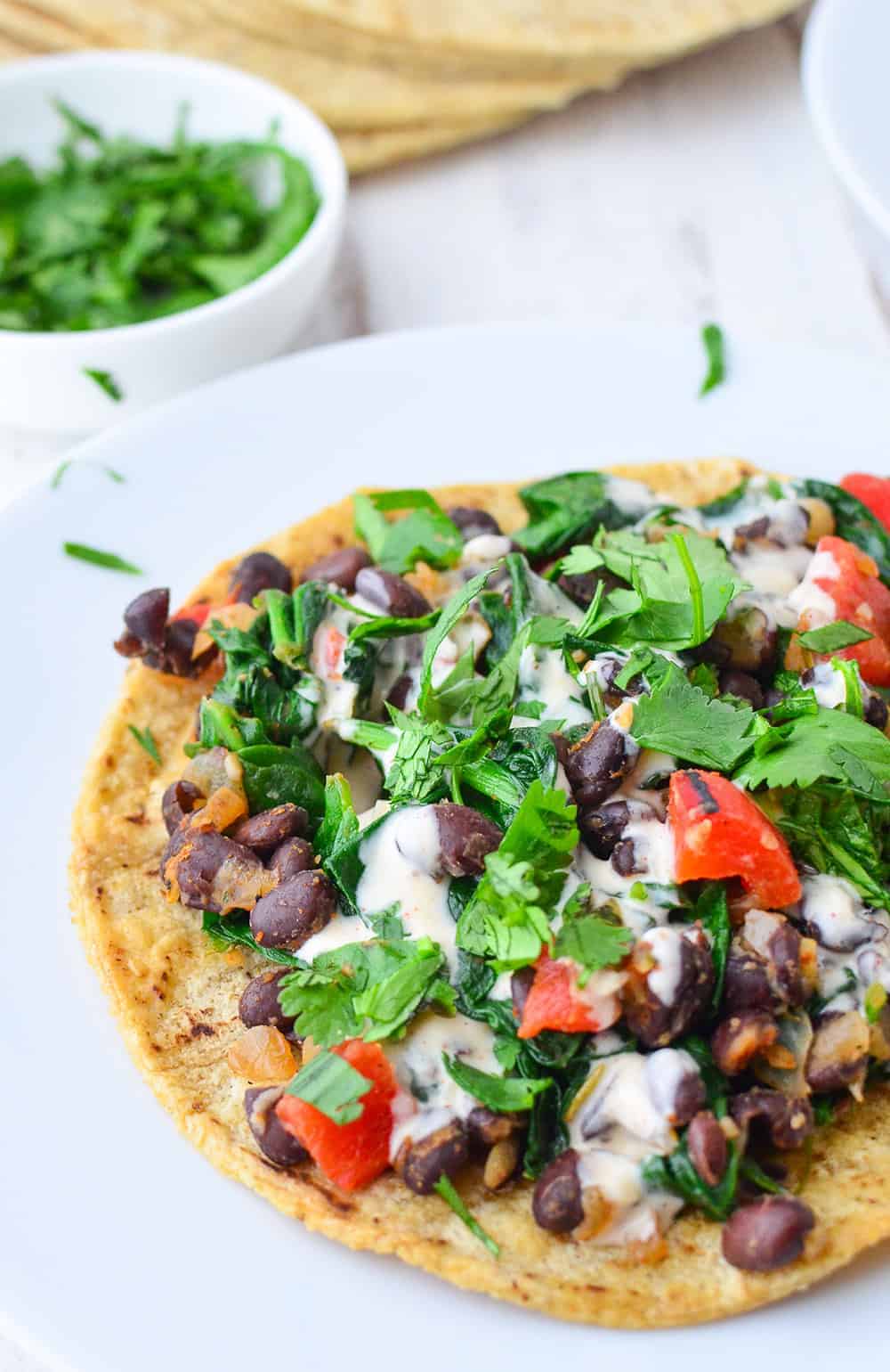 Smoky Black Bean Tostadas! Black bean and spinach filling topped with a smoky paprika sauce. Vegan and gluten-free. | www.delishknowledge.com