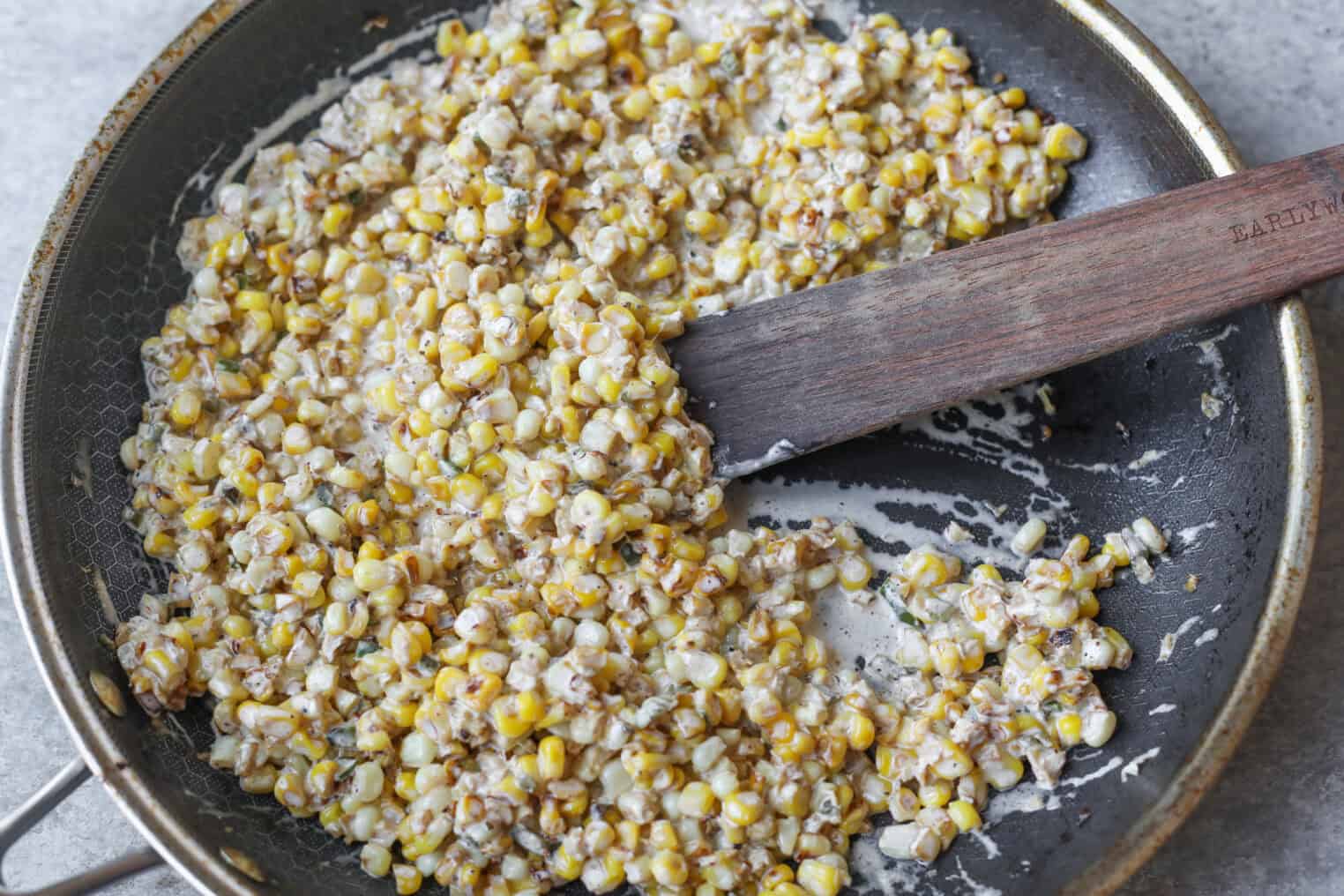 Easy Street Corn Tostadas 5 A Skillet Filled With Sautéed Street Corn Kernels Mixed With A Creamy Sauce, Being Stirred With A Wooden Spatula.