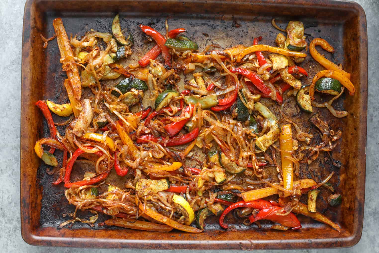 A Baking Sheet With Roasted Mixed Vegetables, Including Sliced Bell Peppers, Onions, And Zucchini—Perfectly Seasoned And Slightly Caramelized For Summer Fajita Bowls.