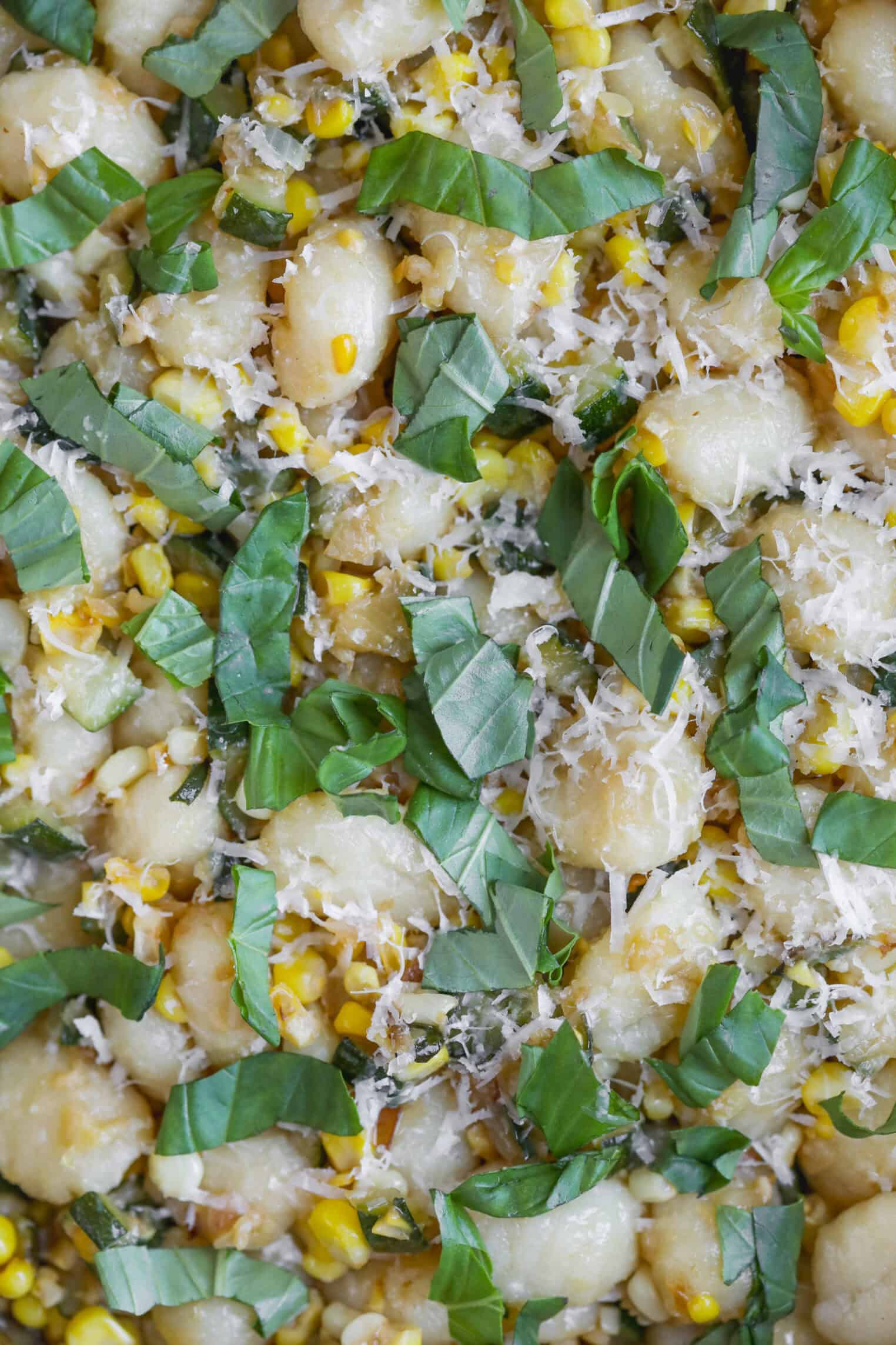 Close-Up Of Summer Gnocchi Mixed With Fresh Corn, Grated Parmesan Cheese, And Basil Leaves, All Brought Together With A Light Zucchini Sauce For A Colorful And Appetizing Dish.