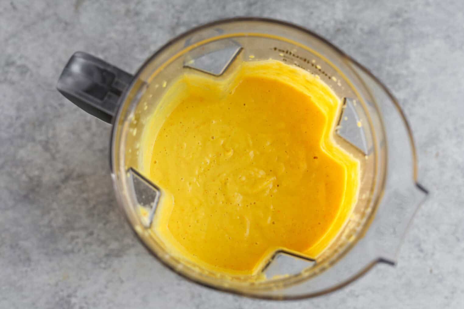 Sun Gold Tomato and Corn Gazpacho 4 A Top-Down View Of A Blender Filled With A Smooth, Bright Yellow Mixture—Possibly Corn Gazpacho Or Sun Gold Tomato Gazpacho—On A Light Gray Countertop.